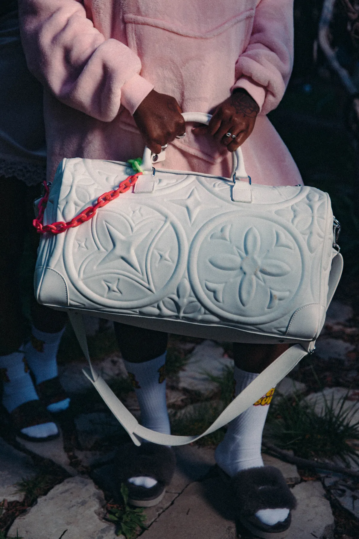 Campaign detail — hands gripping the embossed Marshmallow Duffle, pink fleece hoodie behind